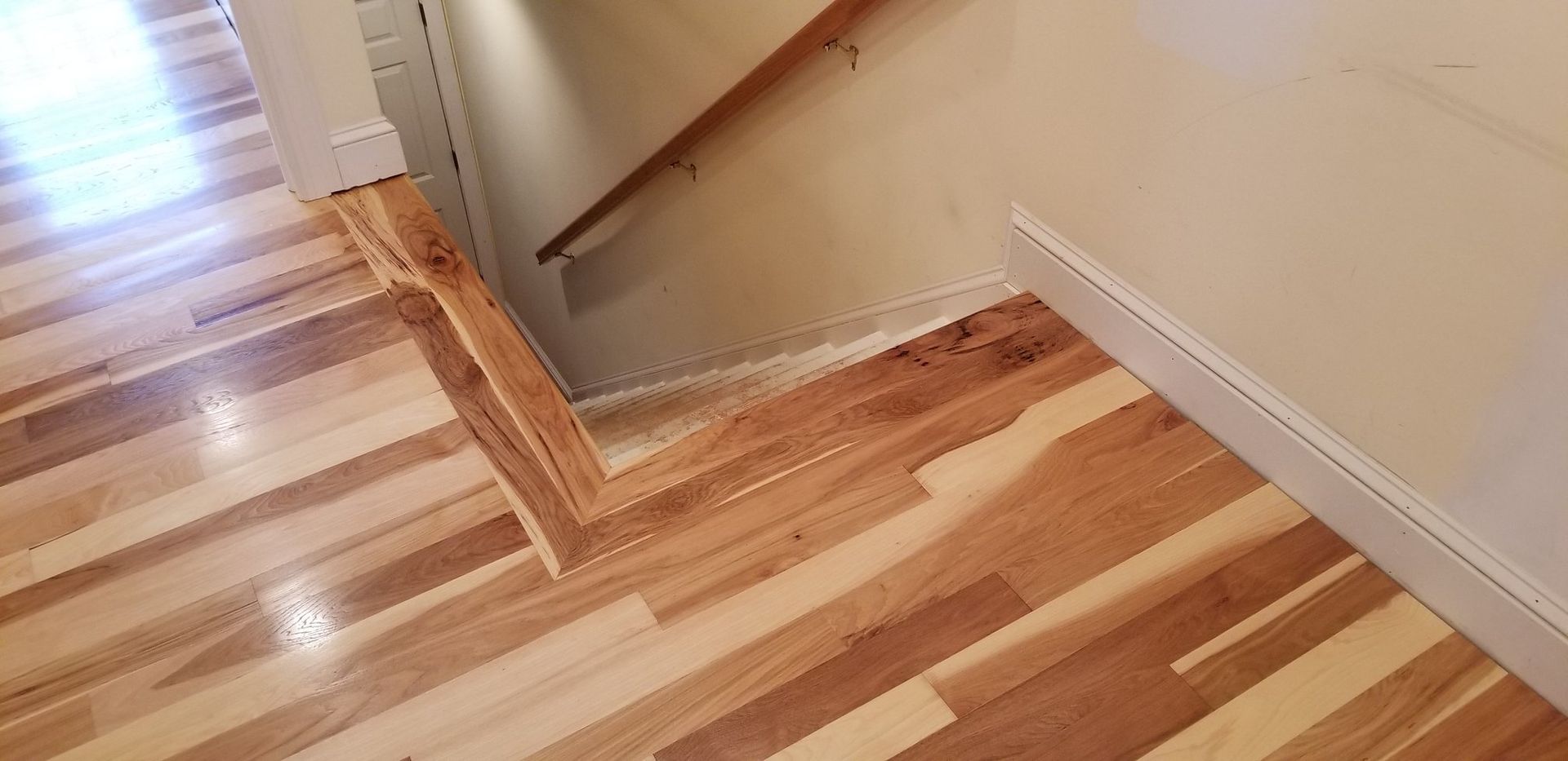 A wooden floor with a staircase in the background.