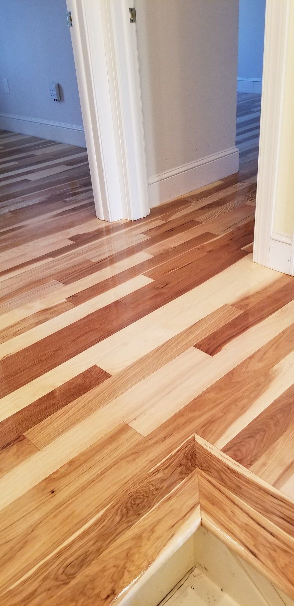 A wooden floor in a room with a door in the background.