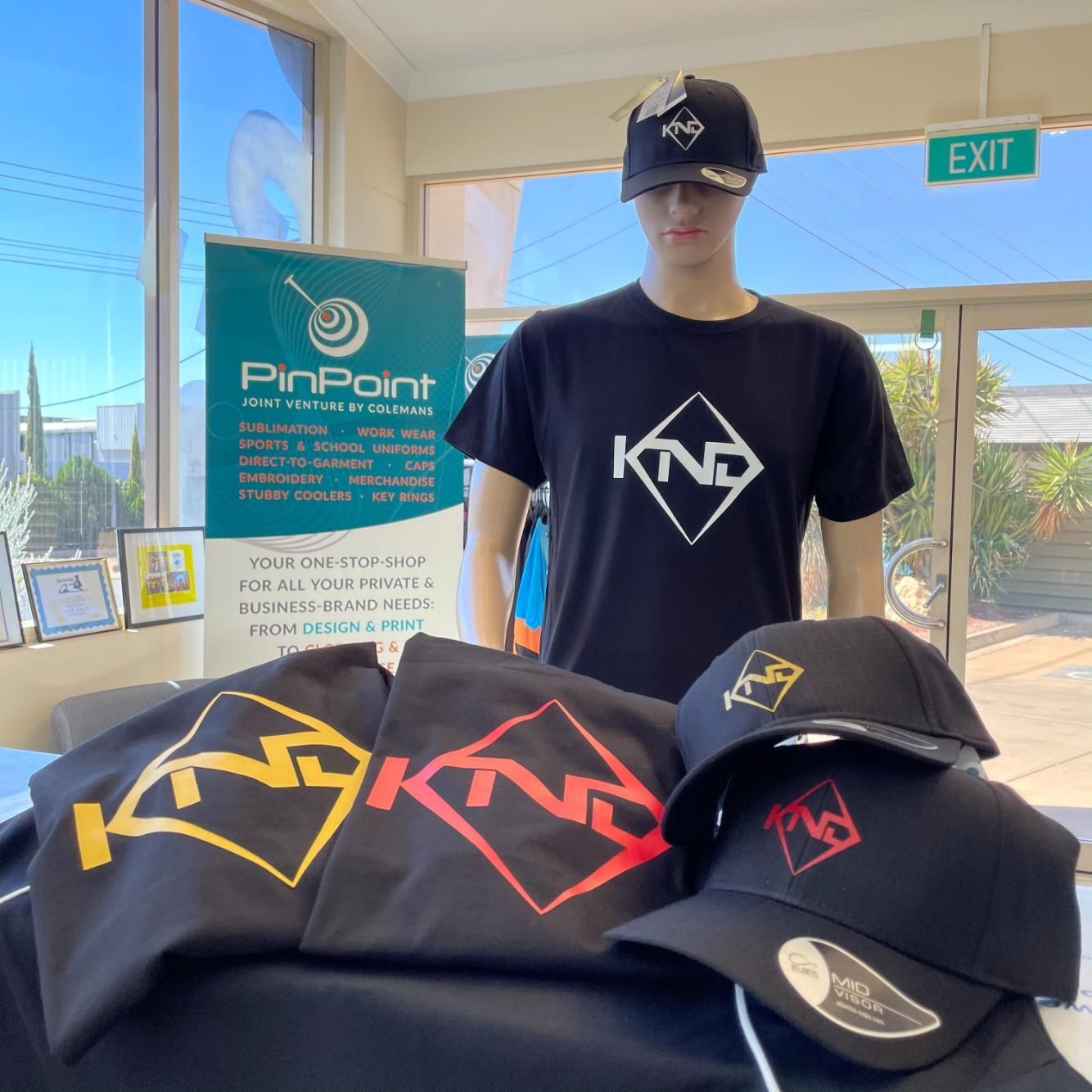 a Man Wearing a Knp T-shirt is Standing Next to a Bunch of Hats — Pinpoint In Alice Springs, NT