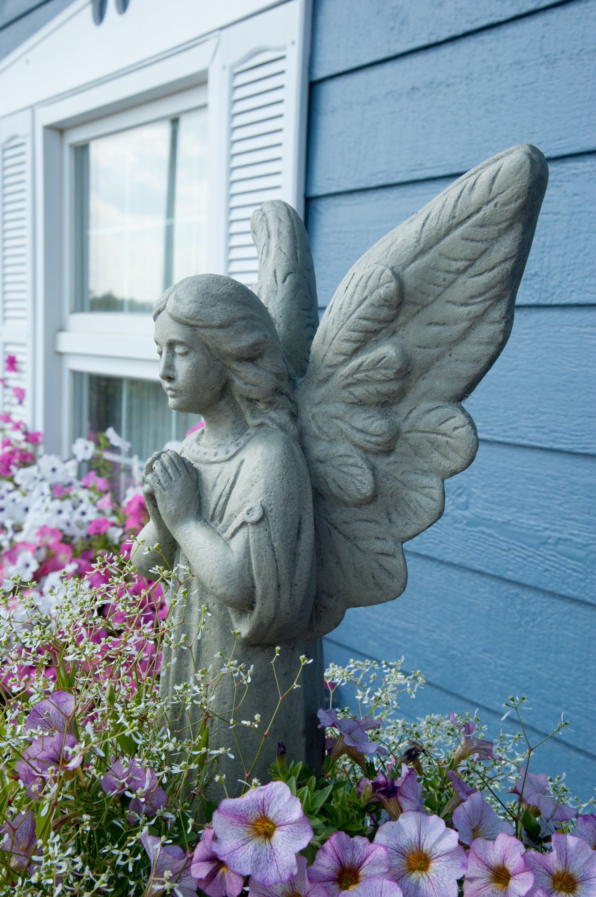 a statue of an angel praying in front of a blue house
