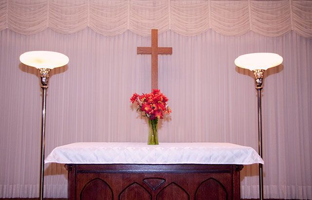 a church altar with a cross and flowers on it