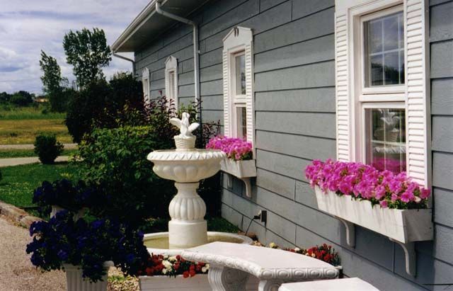 a house with a fountain and flowers in front of it .