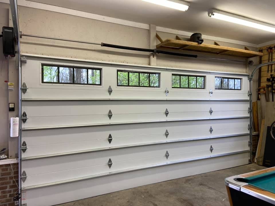 A garage with a pool table and a large white garage door.