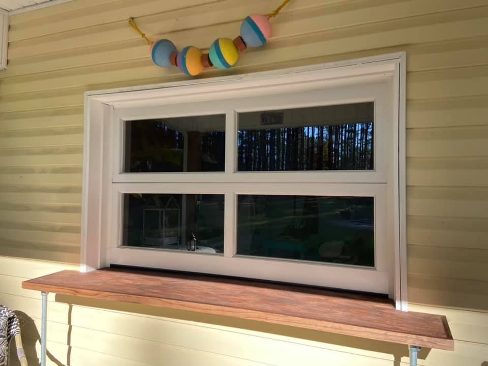 A window on the side of a house with a wooden shelf underneath it