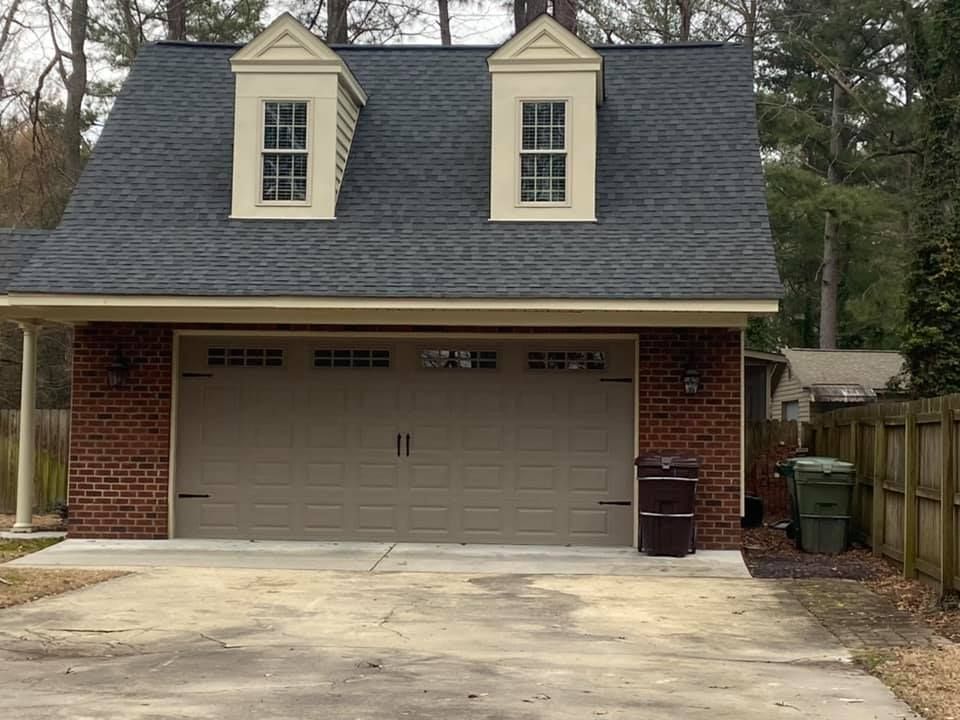 A brick garage with a roof and two windows