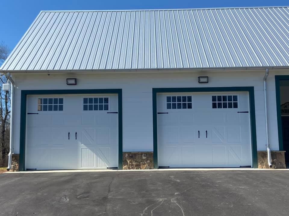 Two white garage doors with green trim and a white roof