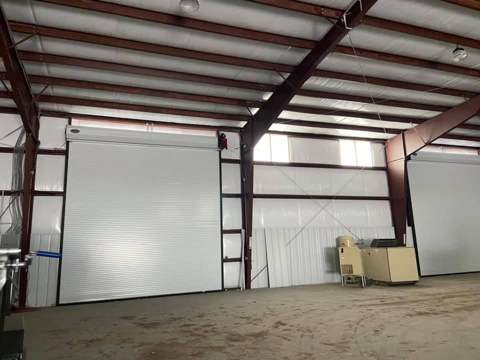 A large warehouse with a large white door and a ladder.