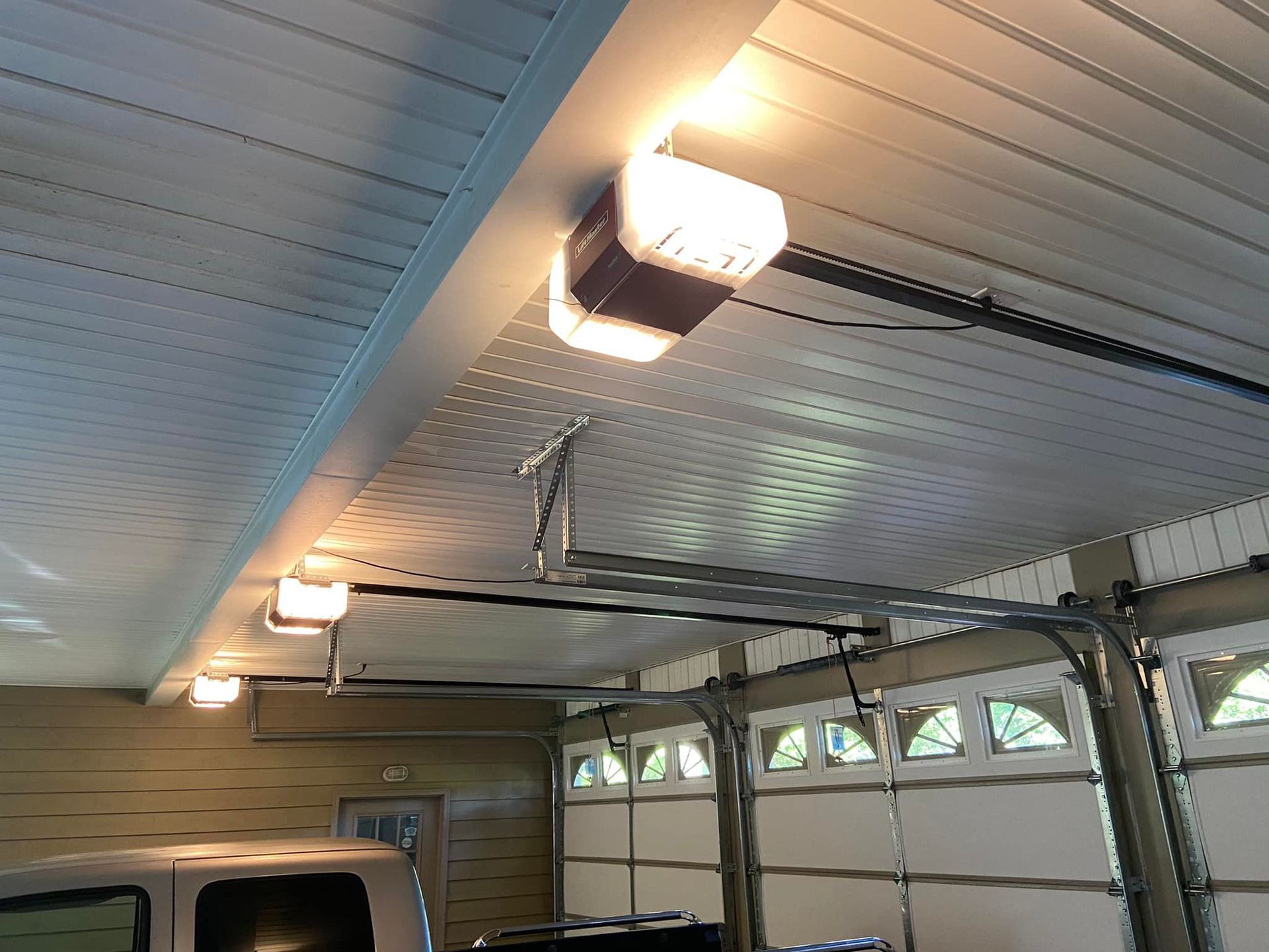 A garage door opener is hanging from the ceiling of a garage.