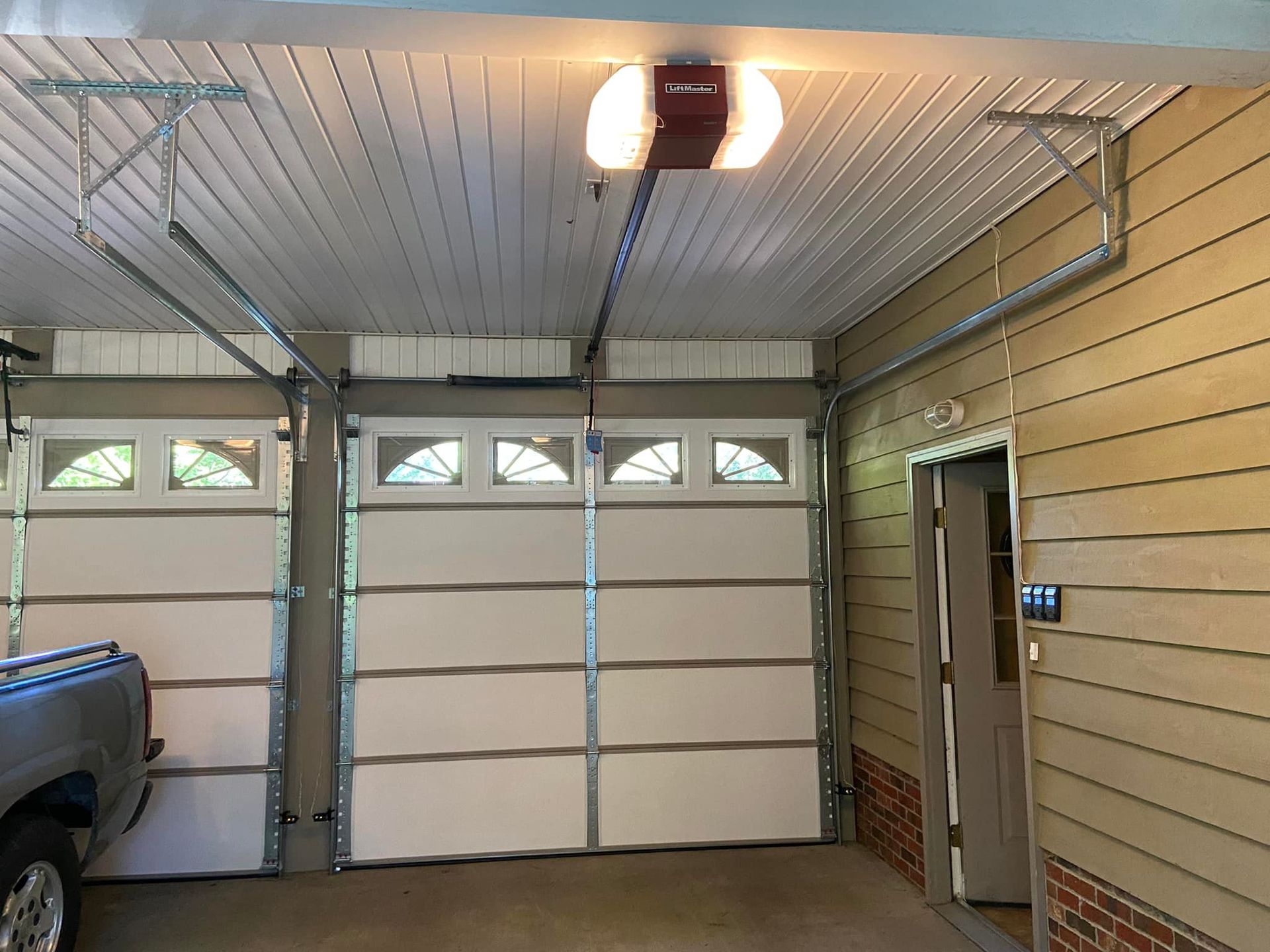 A truck is parked in a garage with a garage door open.
