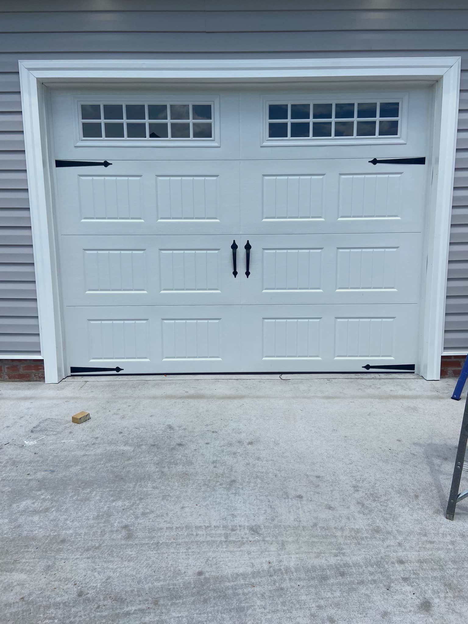 A white garage door is sitting on the side of a house.