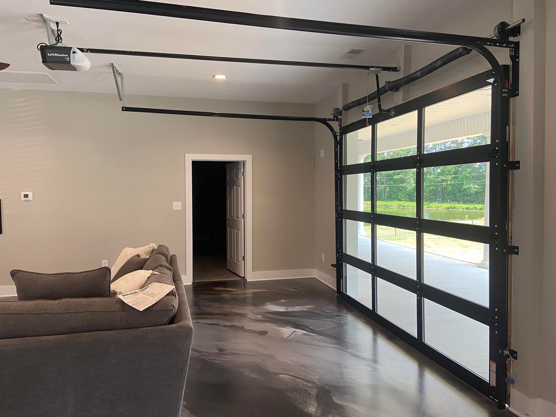 A living room with a couch and a garage door open.
