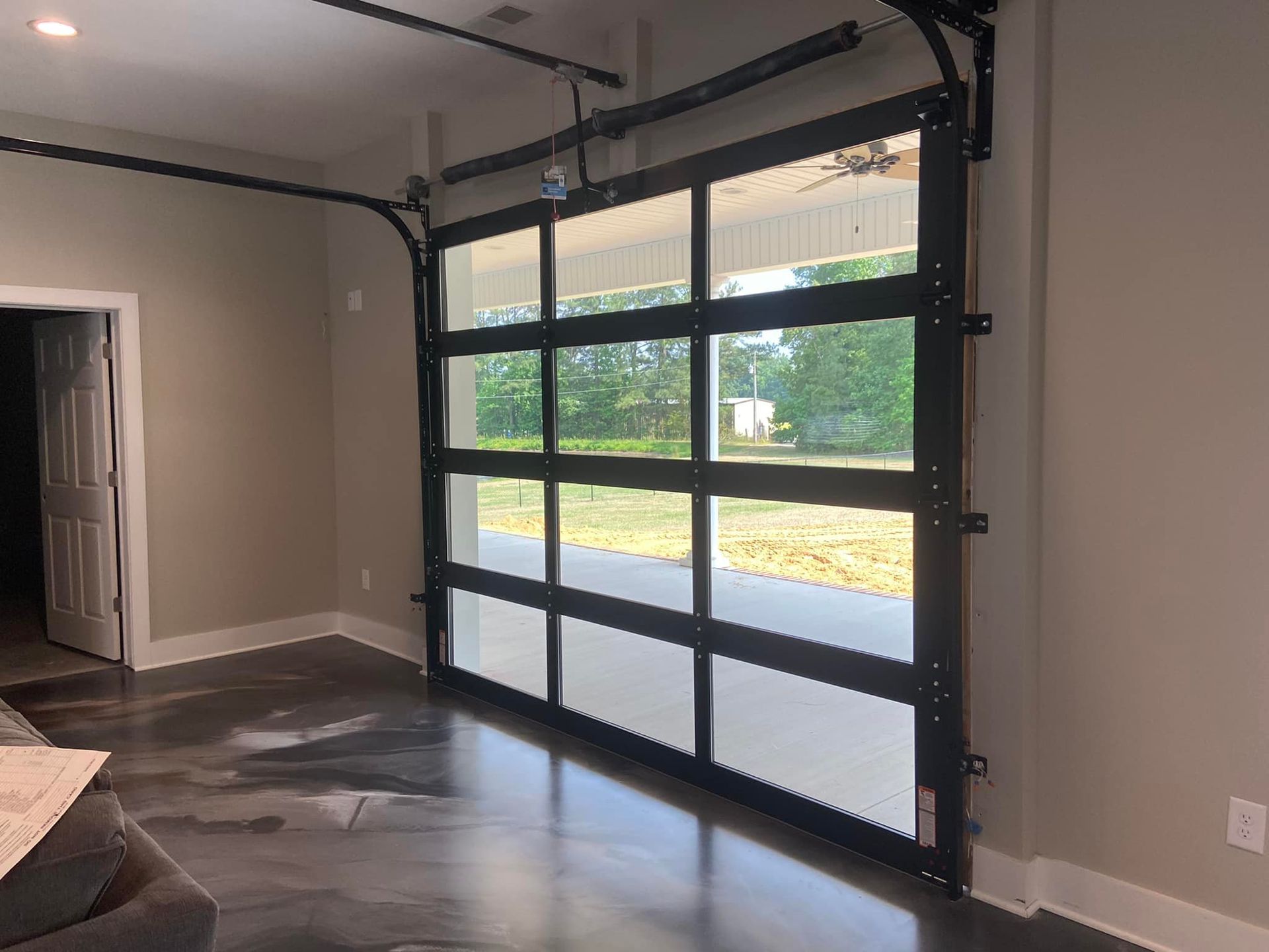 A garage door with a lot of windows is open in a living room.
