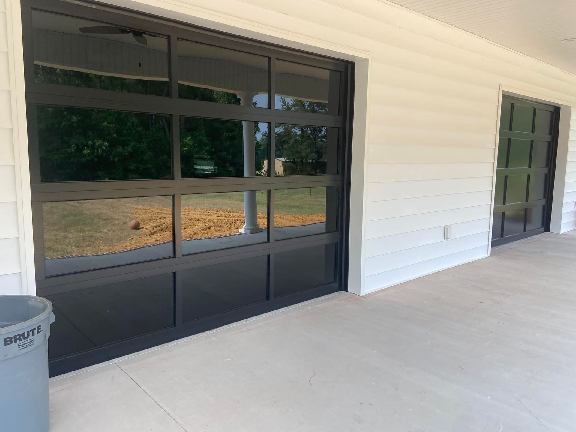 A black garage door with a lot of windows on a white house.