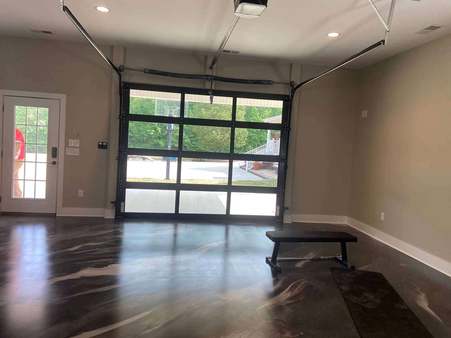 An empty garage with a large garage door and a bench.