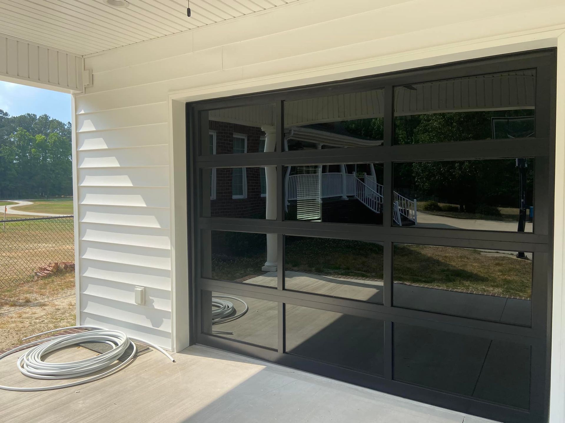 A black garage door is sitting on a porch next to a white house.