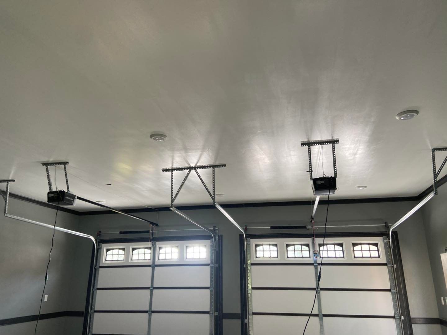 A garage with two garage doors open and a ceiling fan.