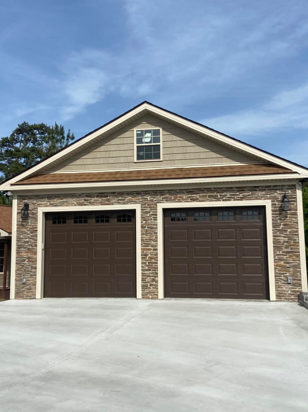 A garage with two brown garage doors and a stone wall