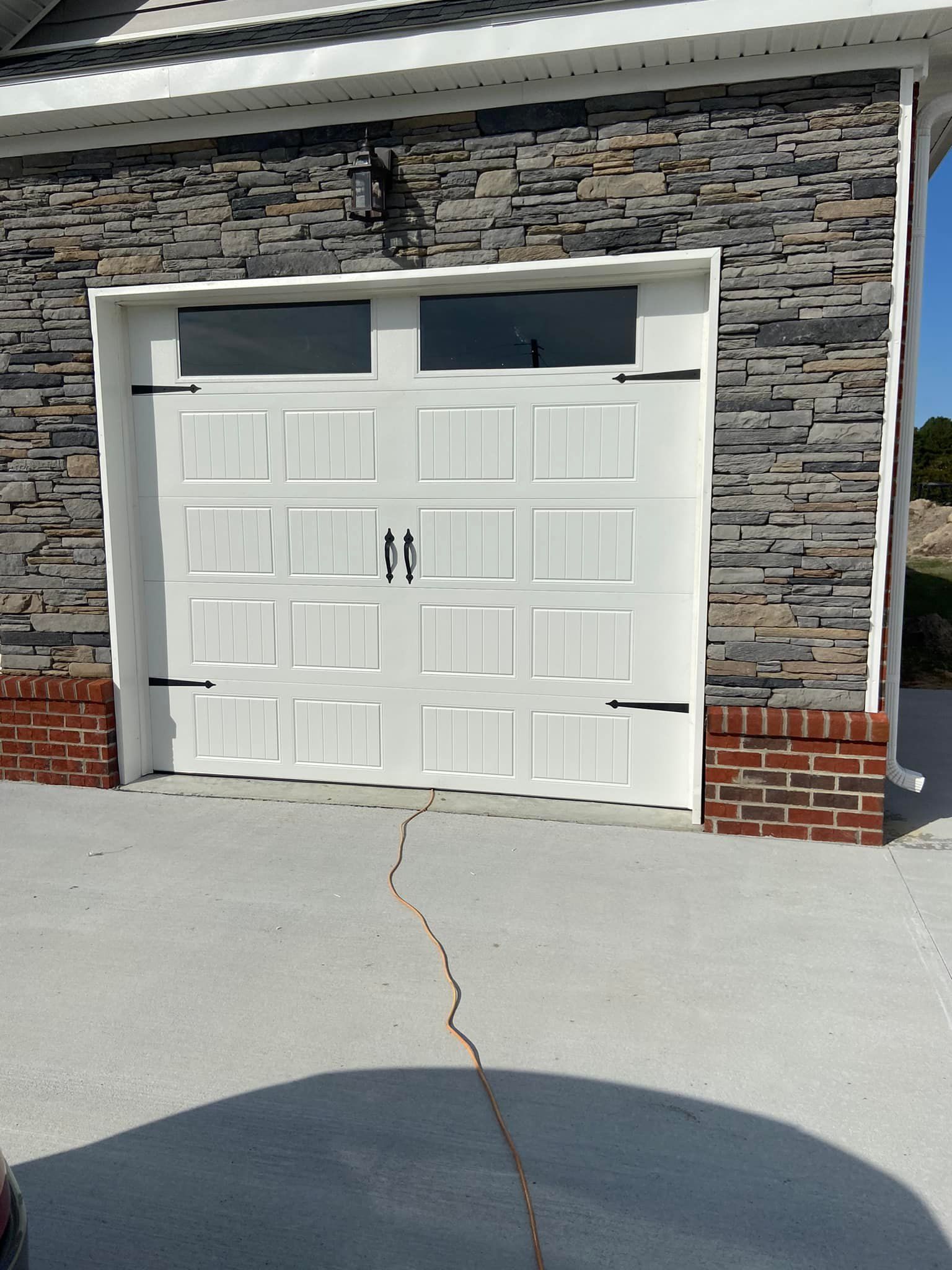 A white garage door with a brick wall behind it