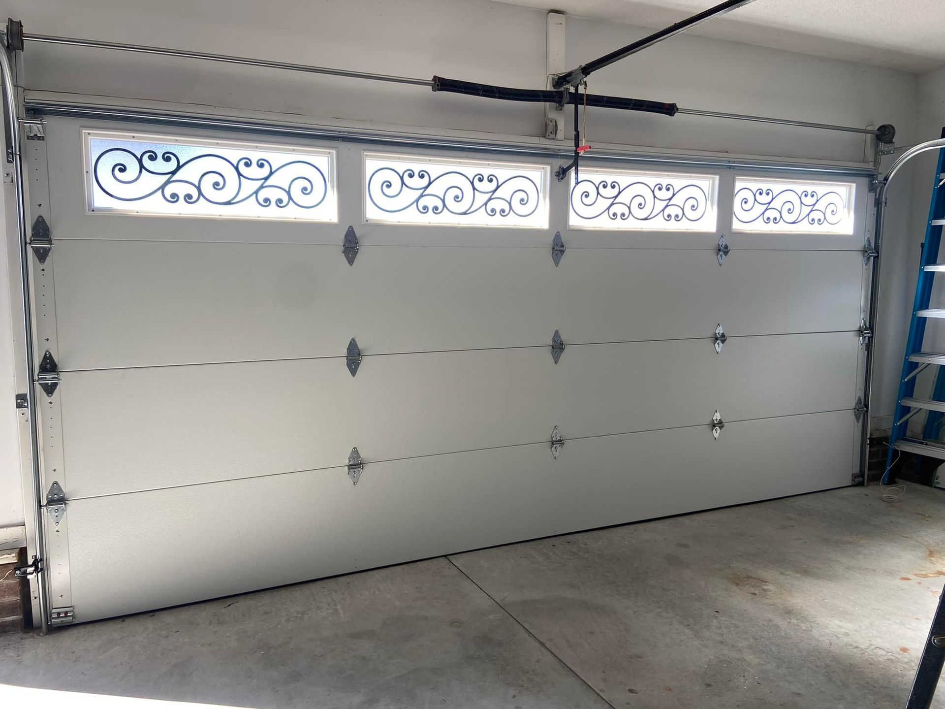 A white garage door with a ladder in the background.