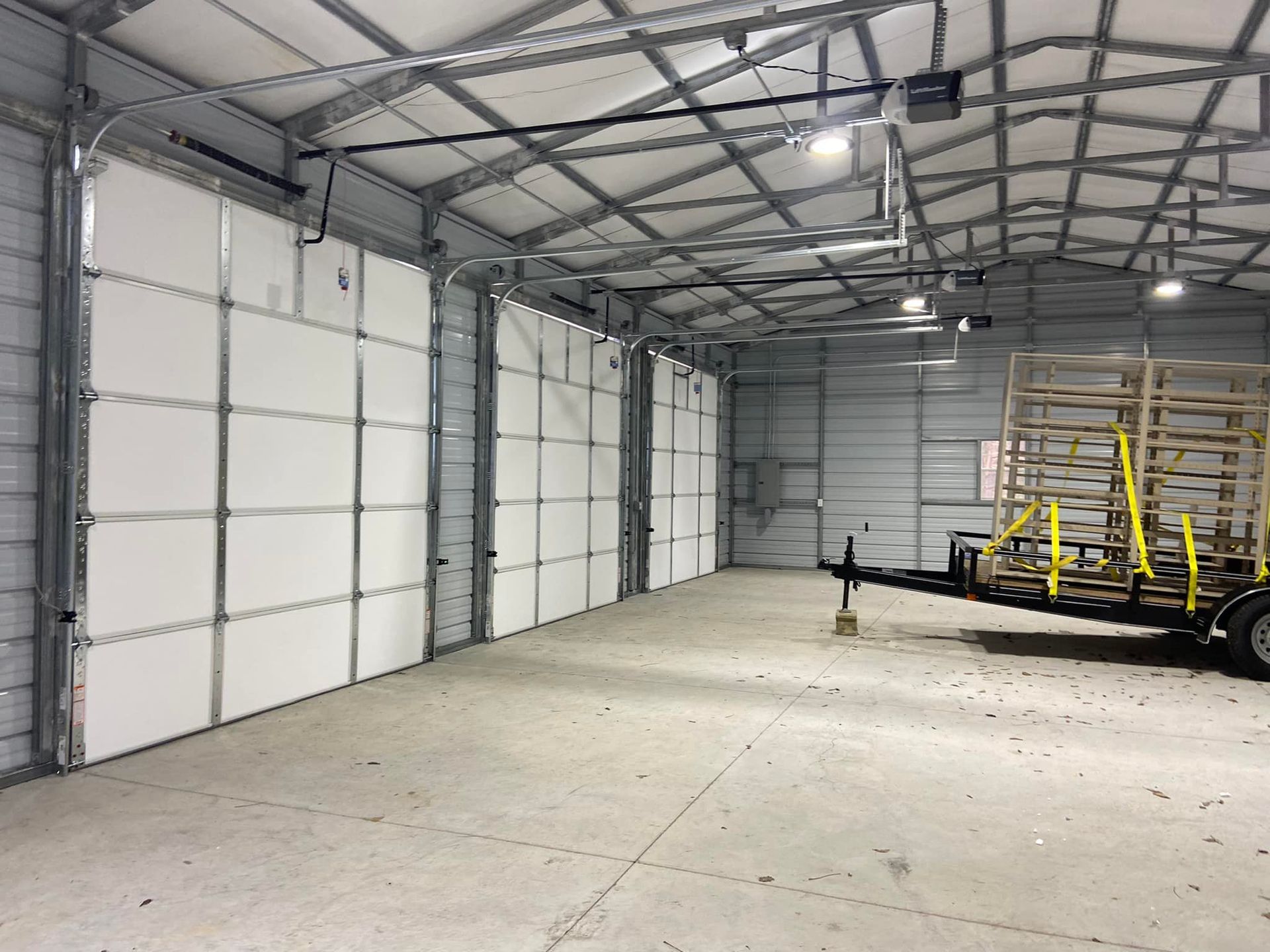 A trailer is parked inside of a garage with a lot of doors.