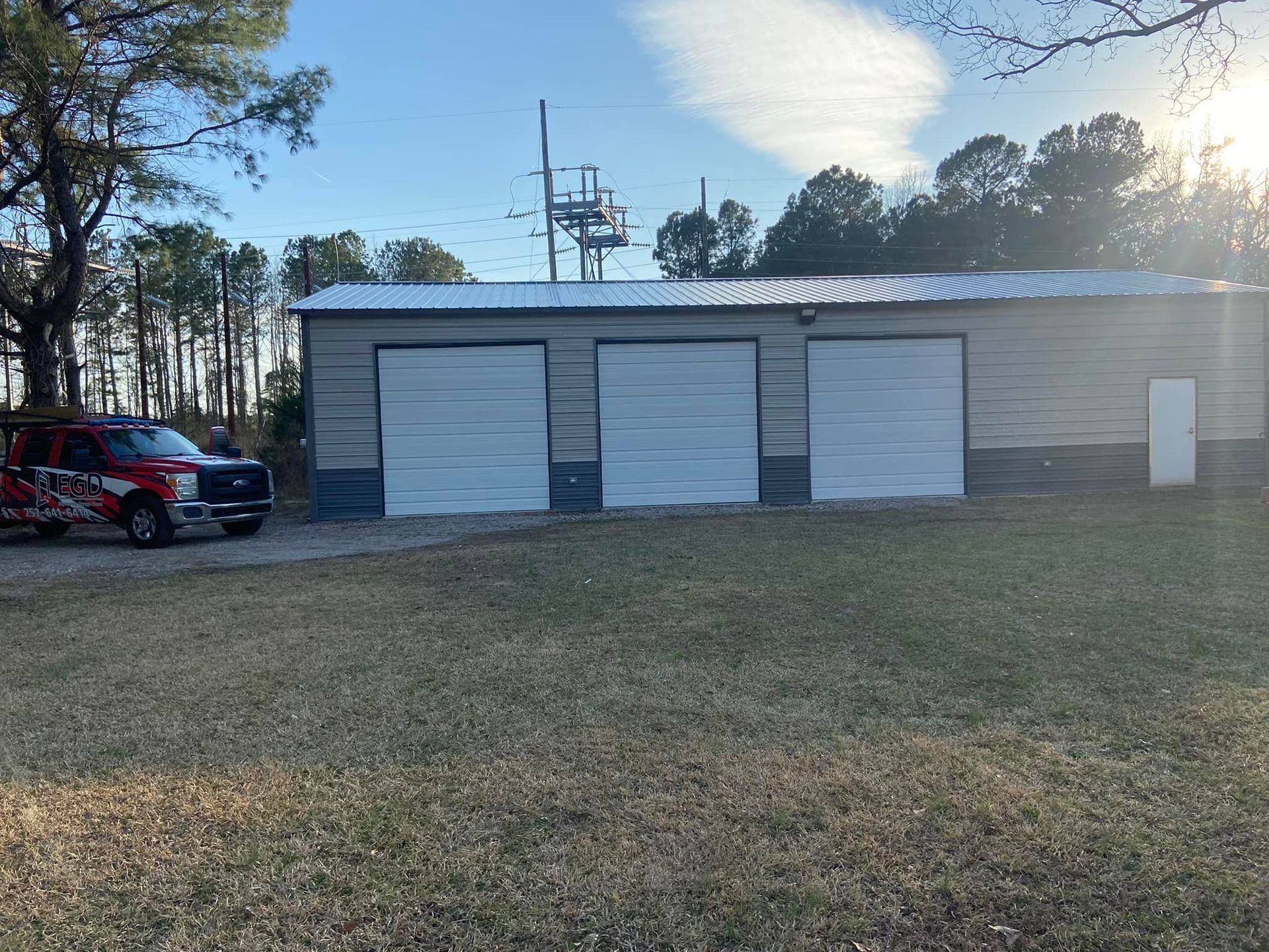 A red truck is parked in front of a garage with three garage doors.