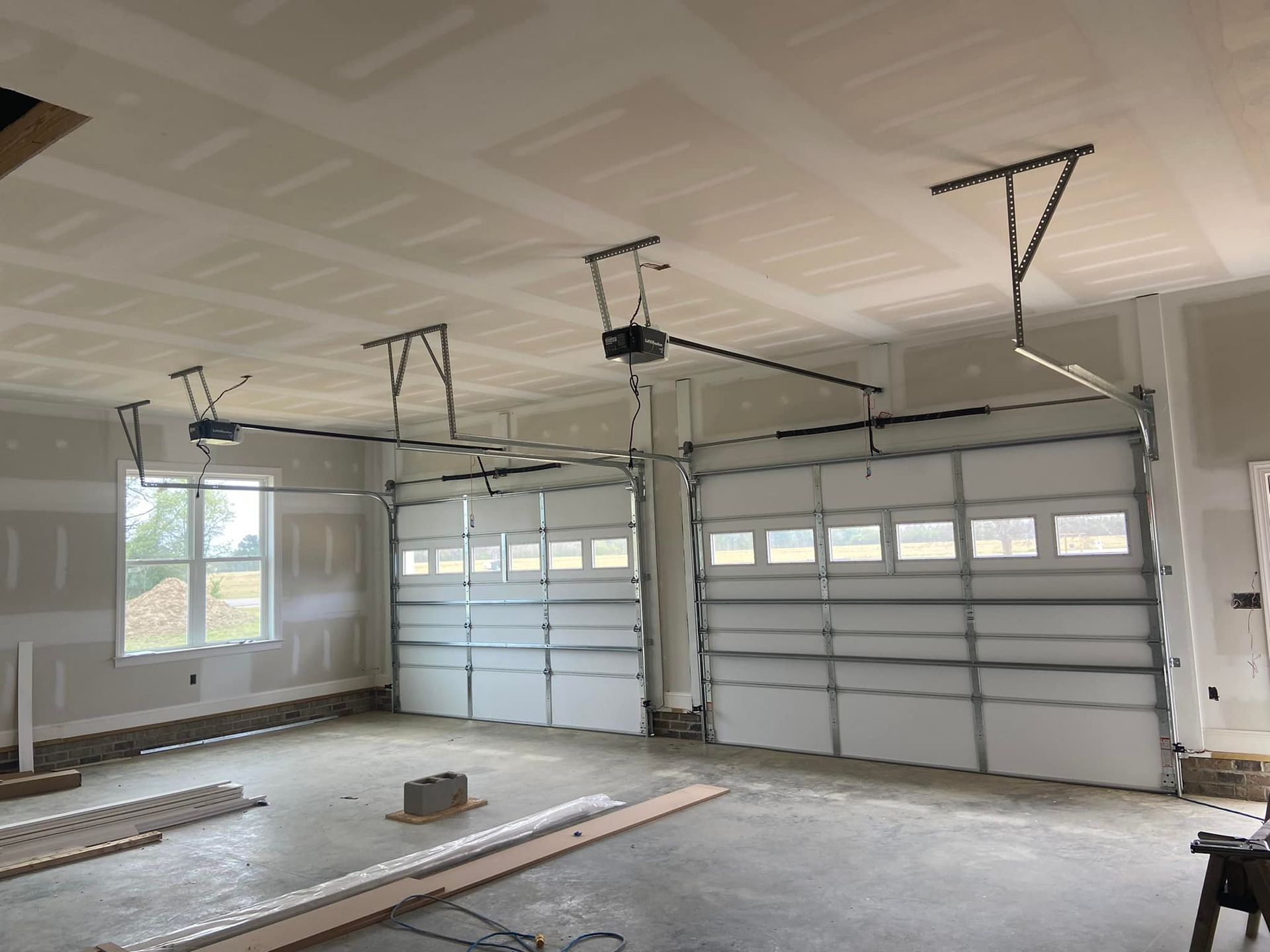 A garage with two garage doors and a ceiling fan.