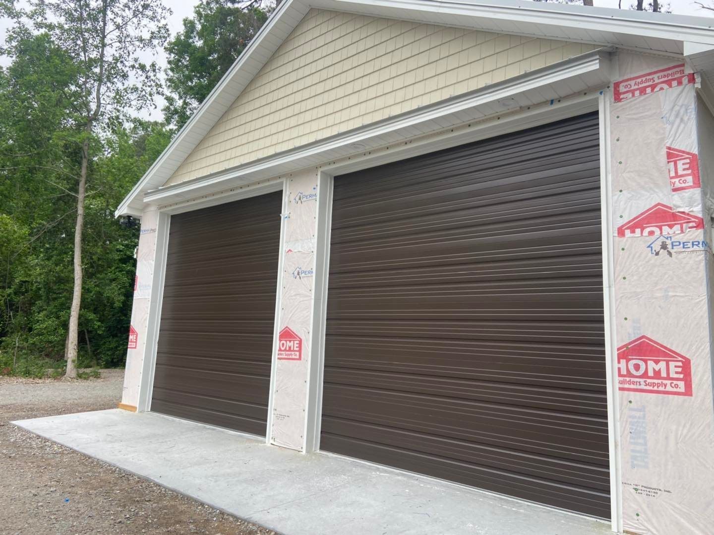 A garage with three brown garage doors is being built.