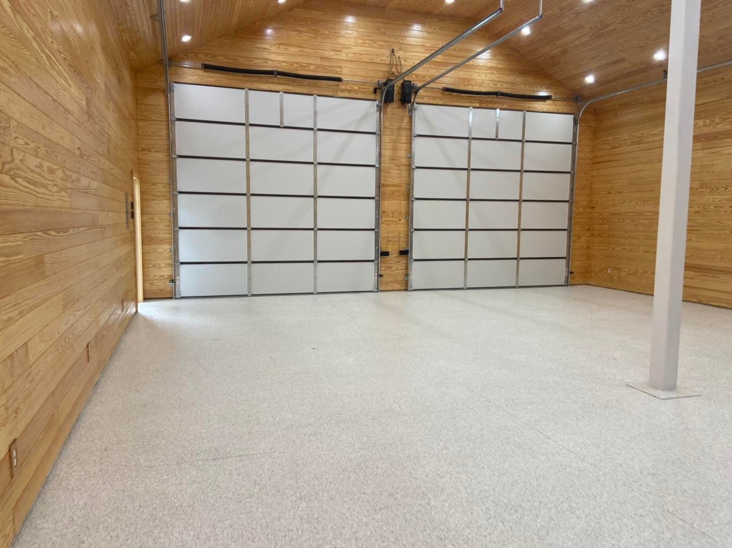 A large garage with two garage doors and a white floor.