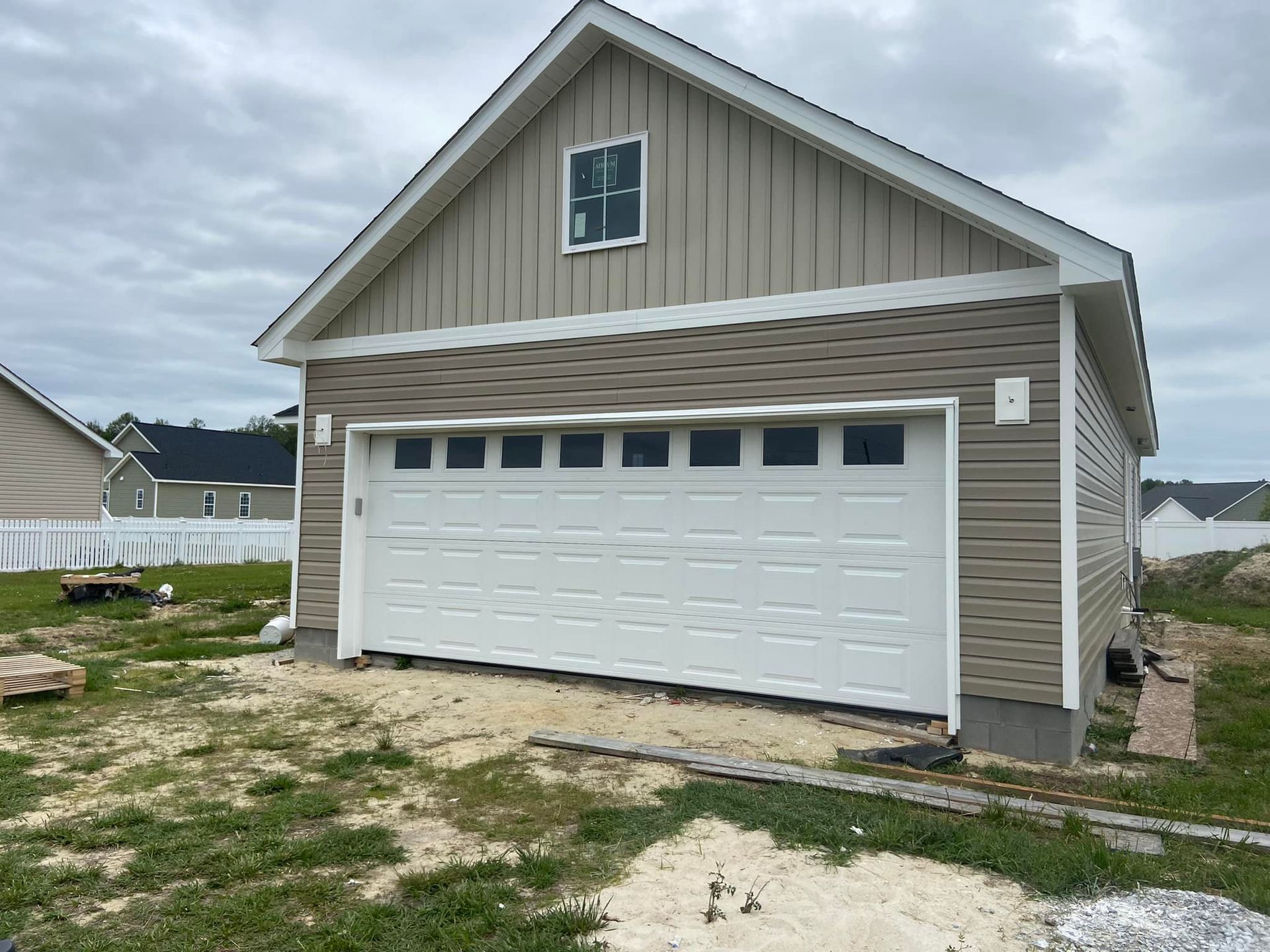 A garage with a white garage door is being built in a yard.