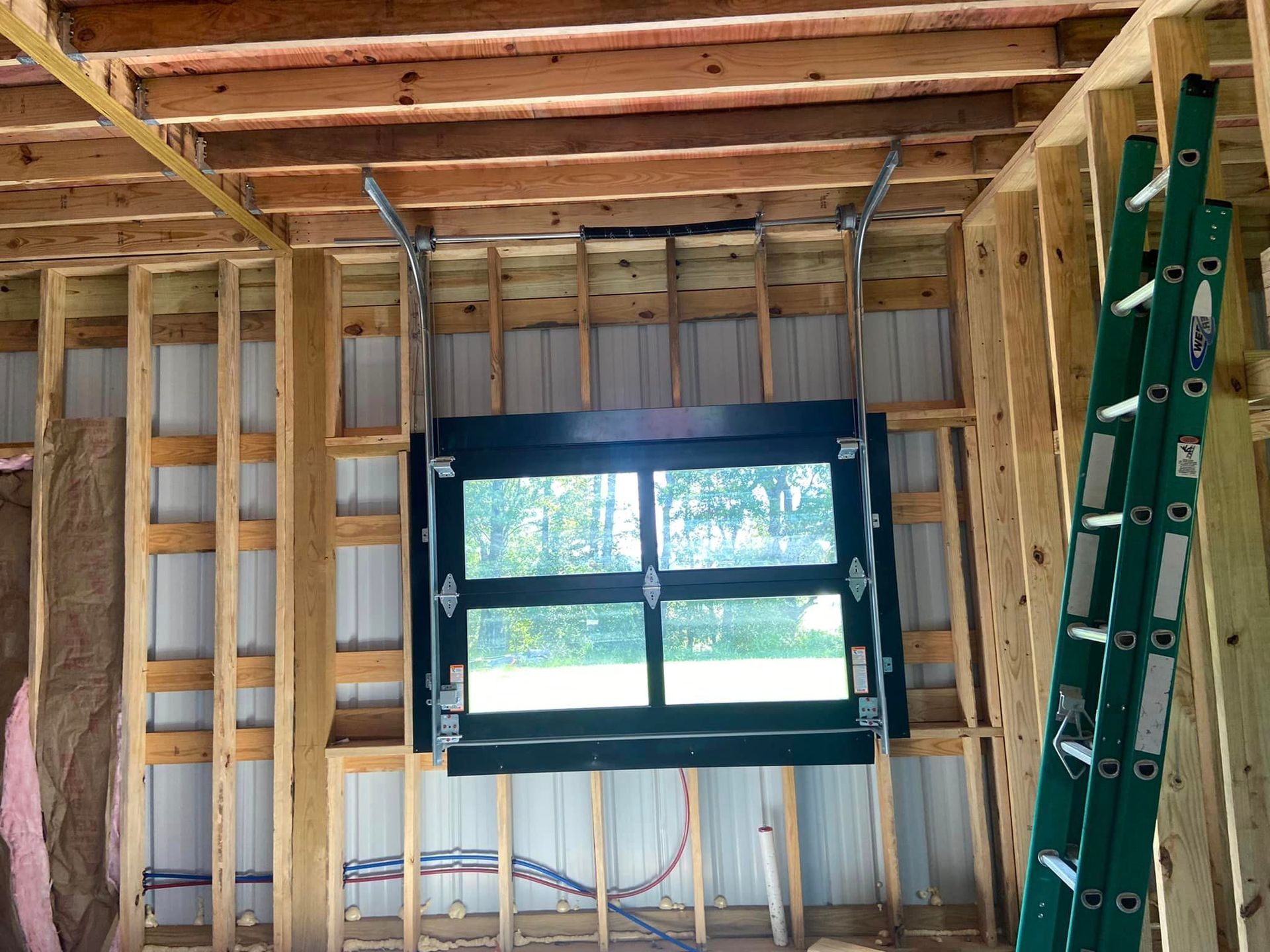 A green ladder is hanging from the ceiling of a building under construction.