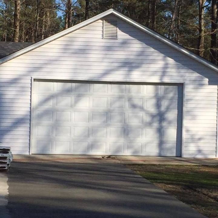 A white garage with a car parked in front of it.