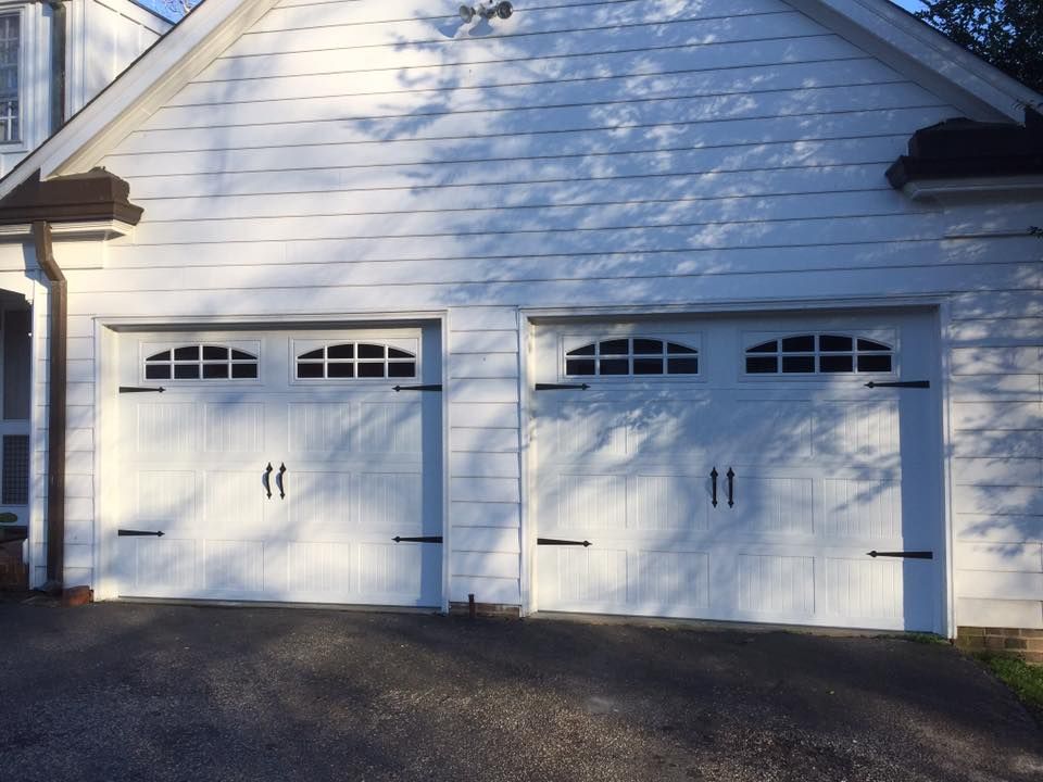 A white house with two garage doors and a driveway