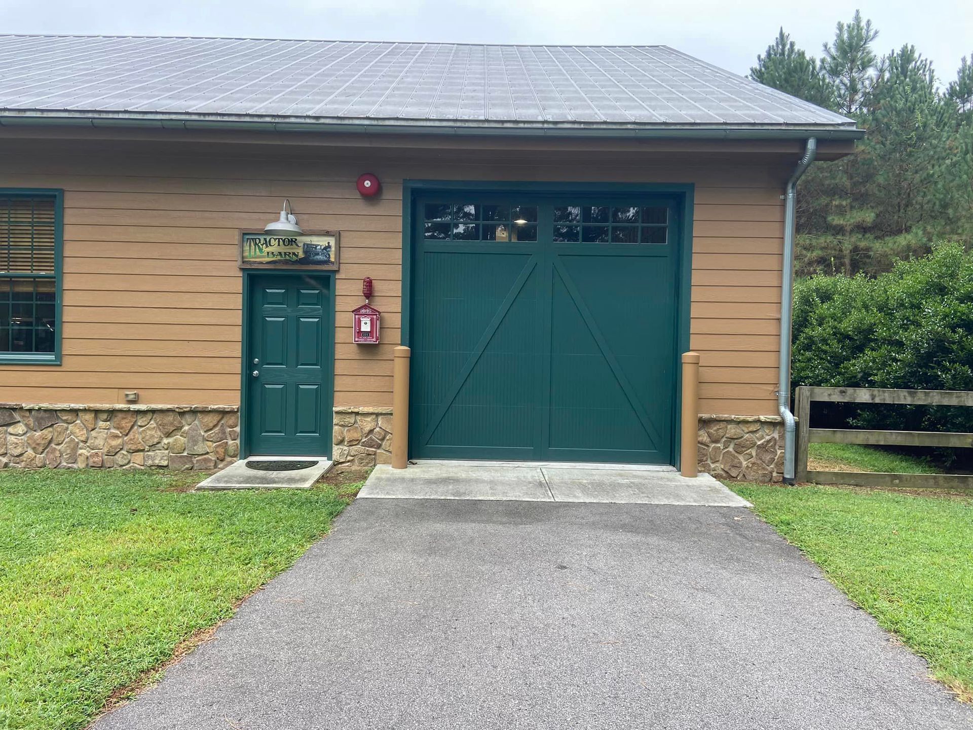 A brown house with a green garage door and a driveway leading to it.