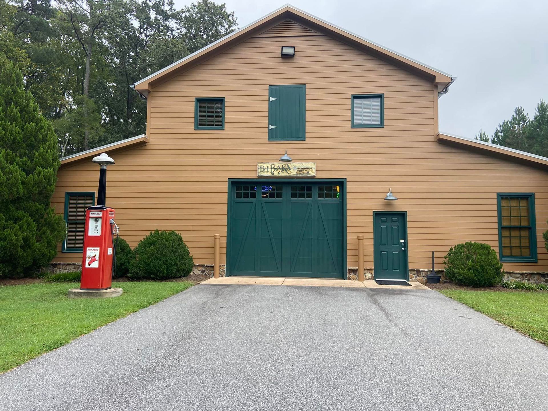 A large barn with a green garage door and a red fire hydrant in front of it