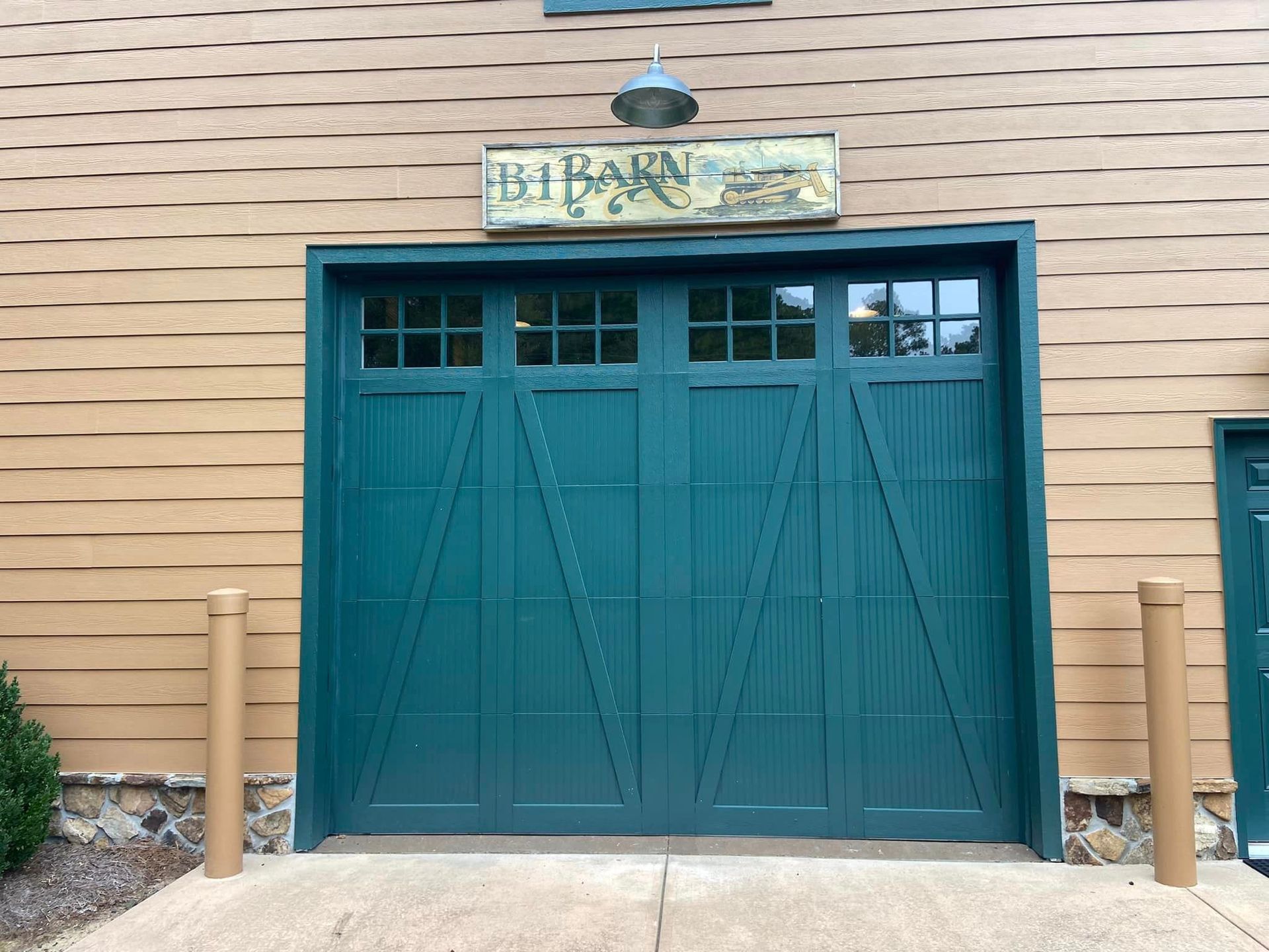 A green garage door with a sign above it that says the barn