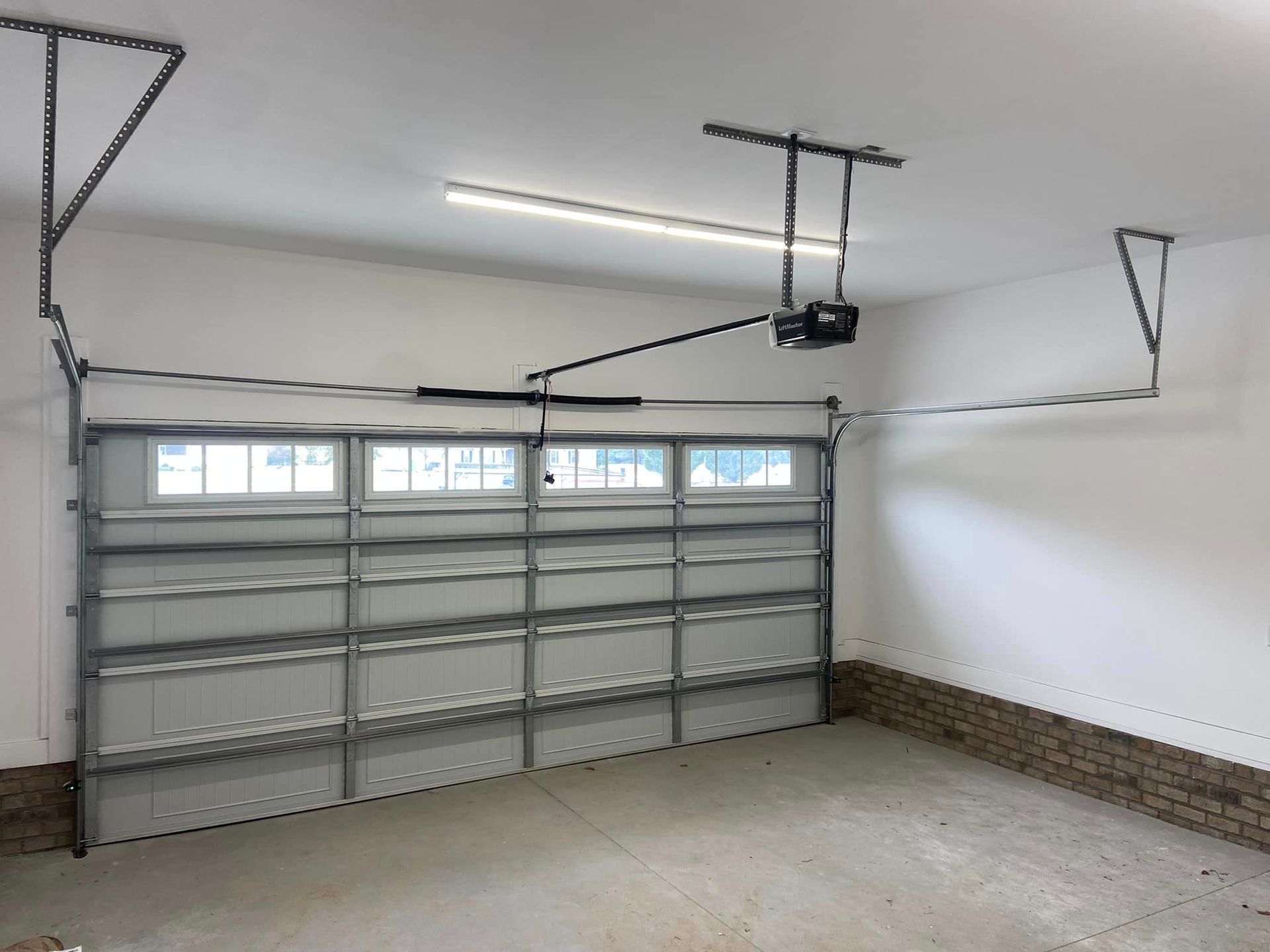An empty garage with a garage door opener hanging from the ceiling.
