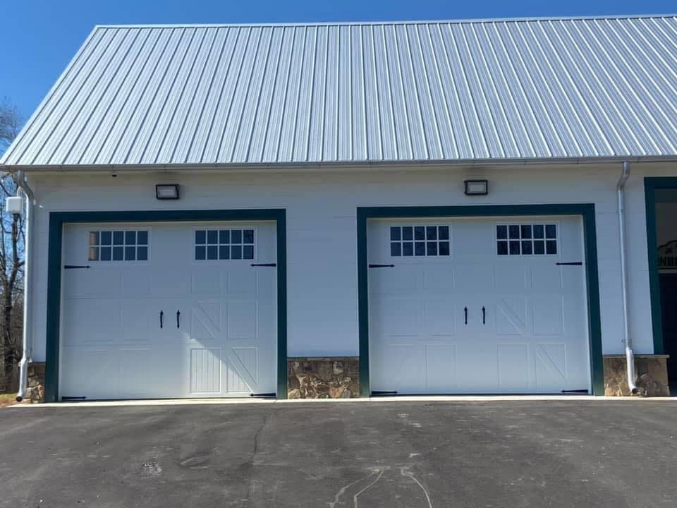 A white garage with two white garage doors and a metal roof.