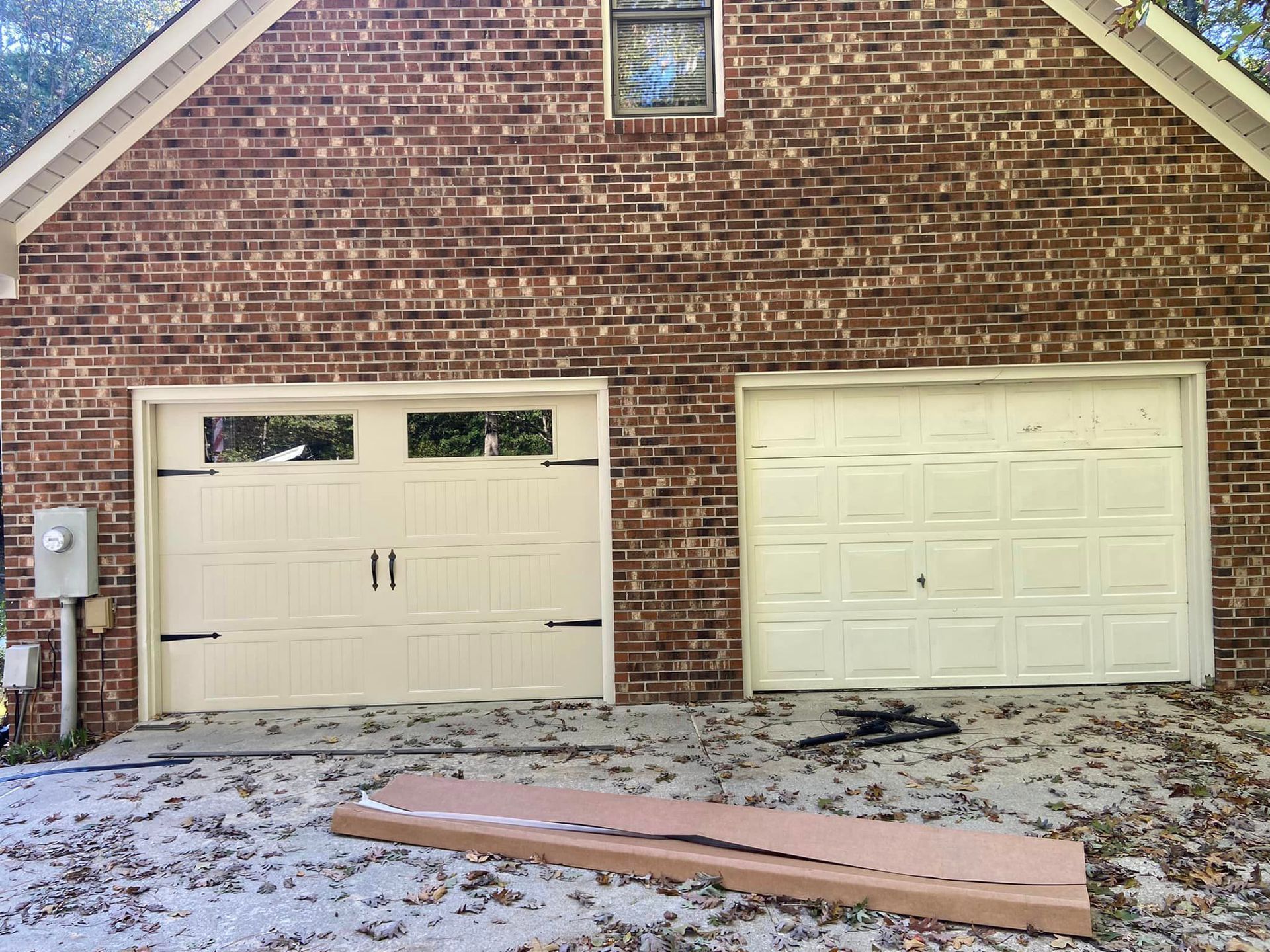 A brick house with two white garage doors on it.