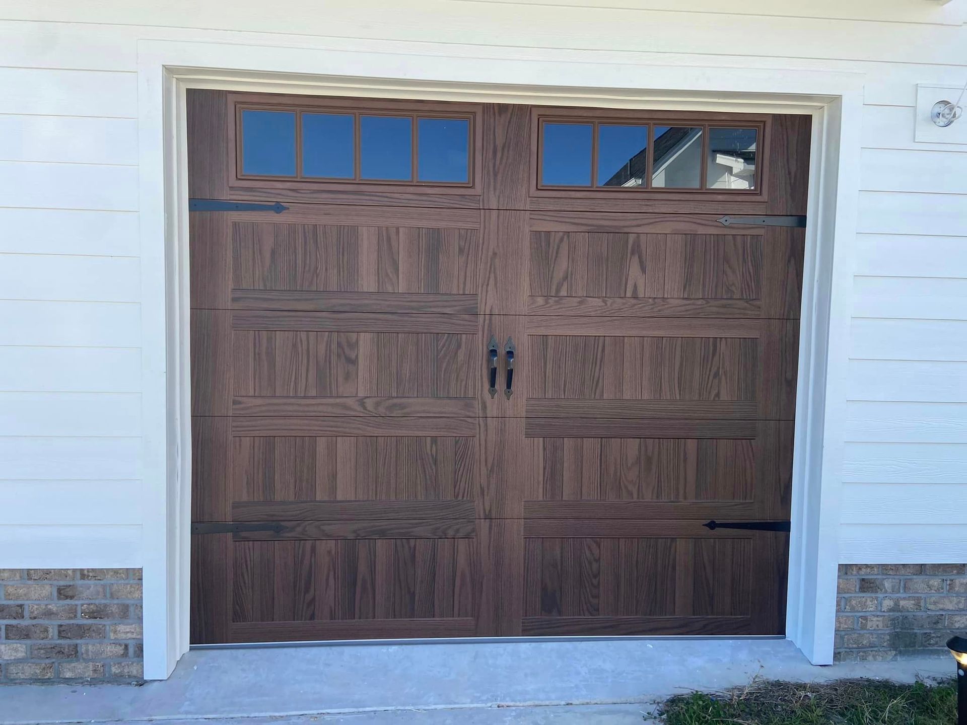 A wooden garage door is sitting on top of a white house.