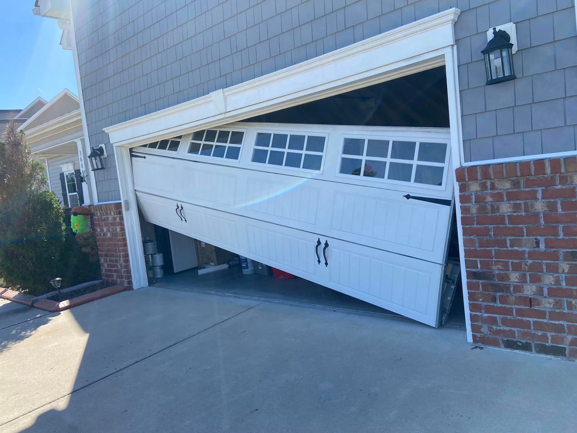 A white garage door has fallen off of a brick building.