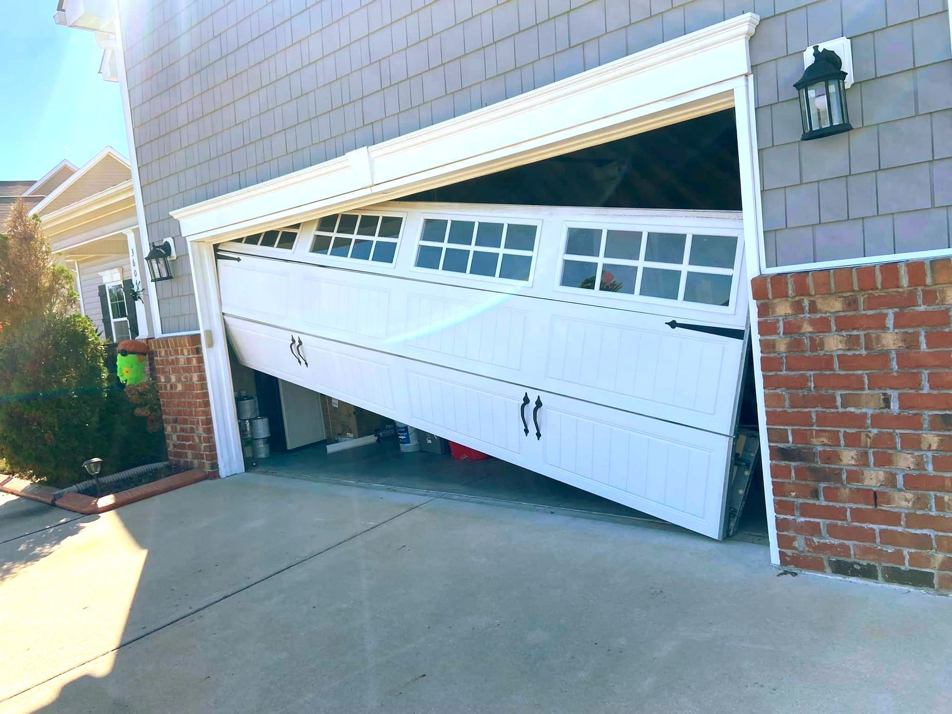 A white garage door is open on the side of a house.