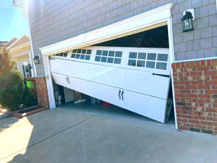 A white garage door is open on the side of a house.