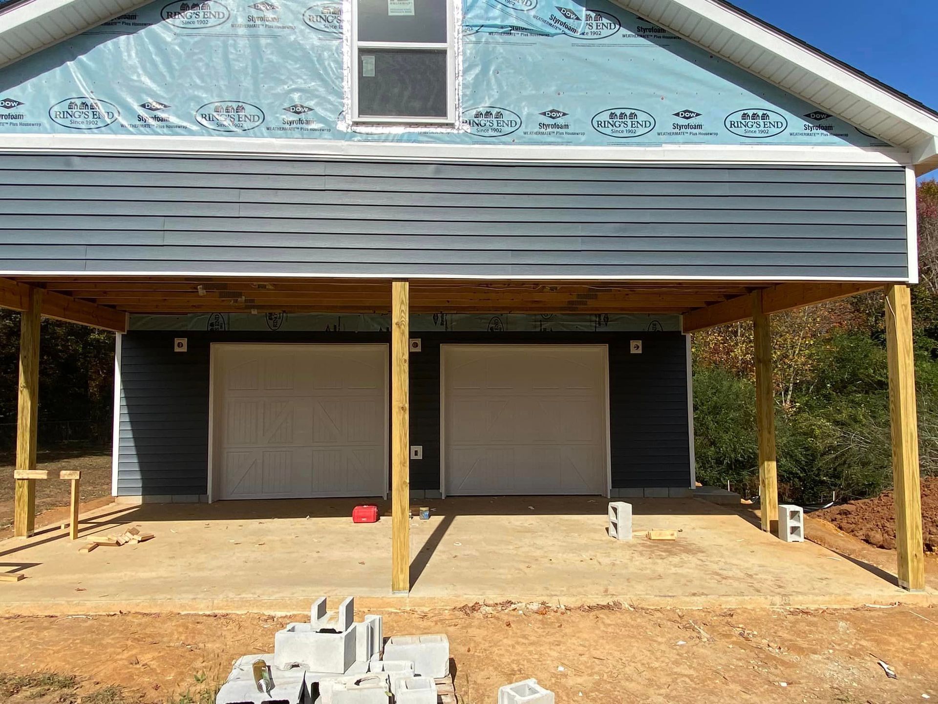 A house under construction with two garage doors and a porch.