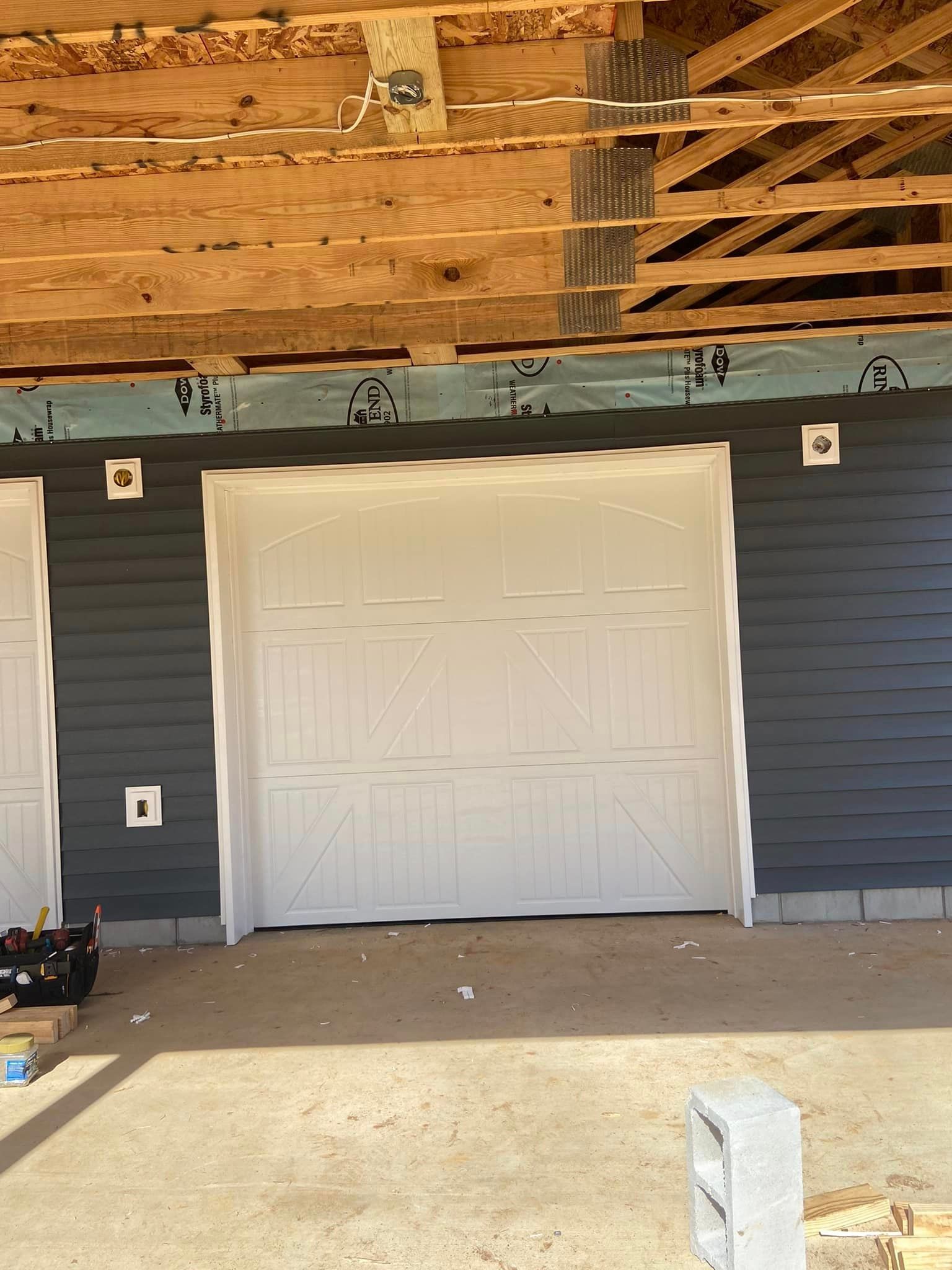 A garage door is being installed in a house under construction.