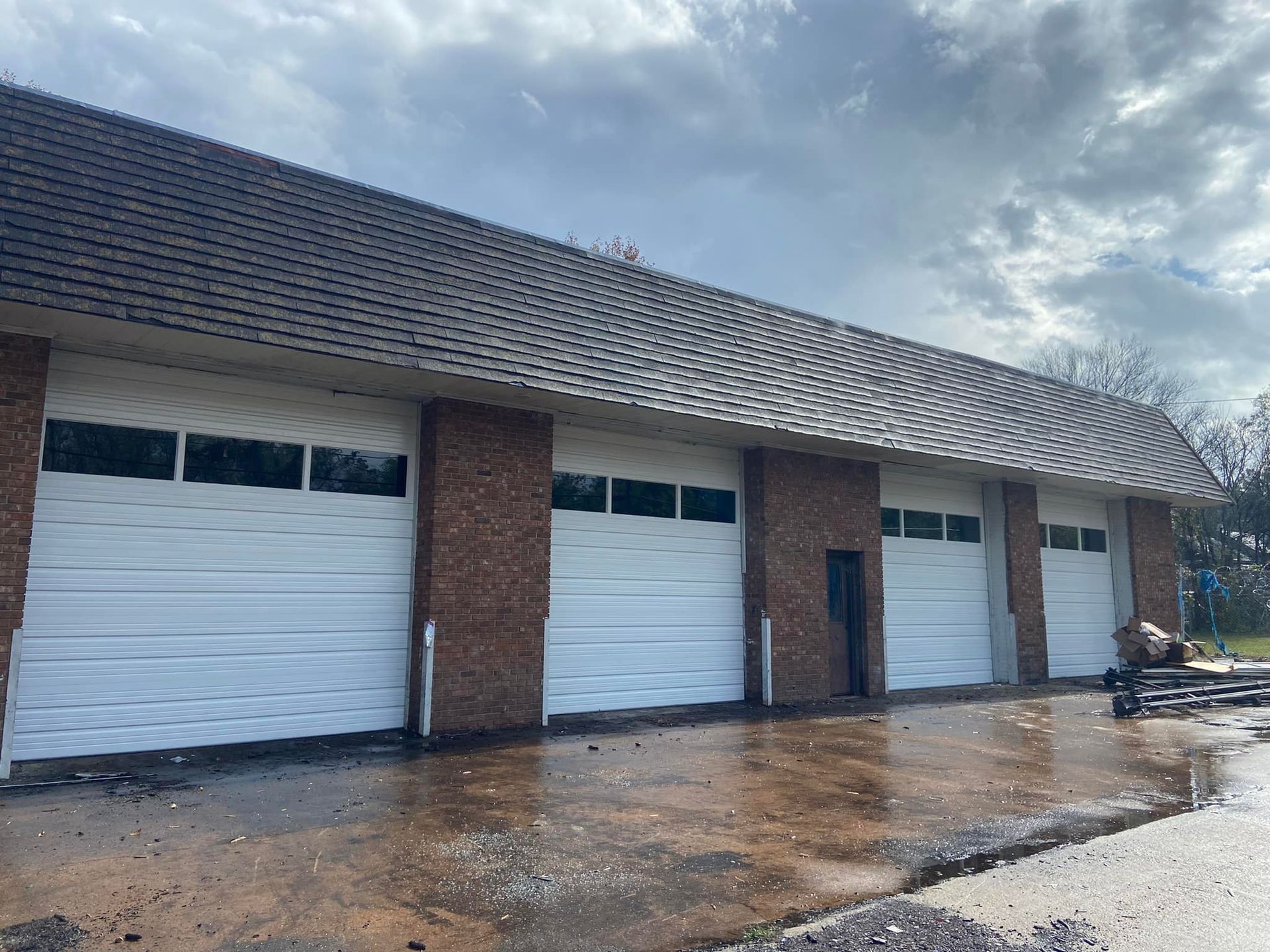 A row of white garage doors on a brick building.