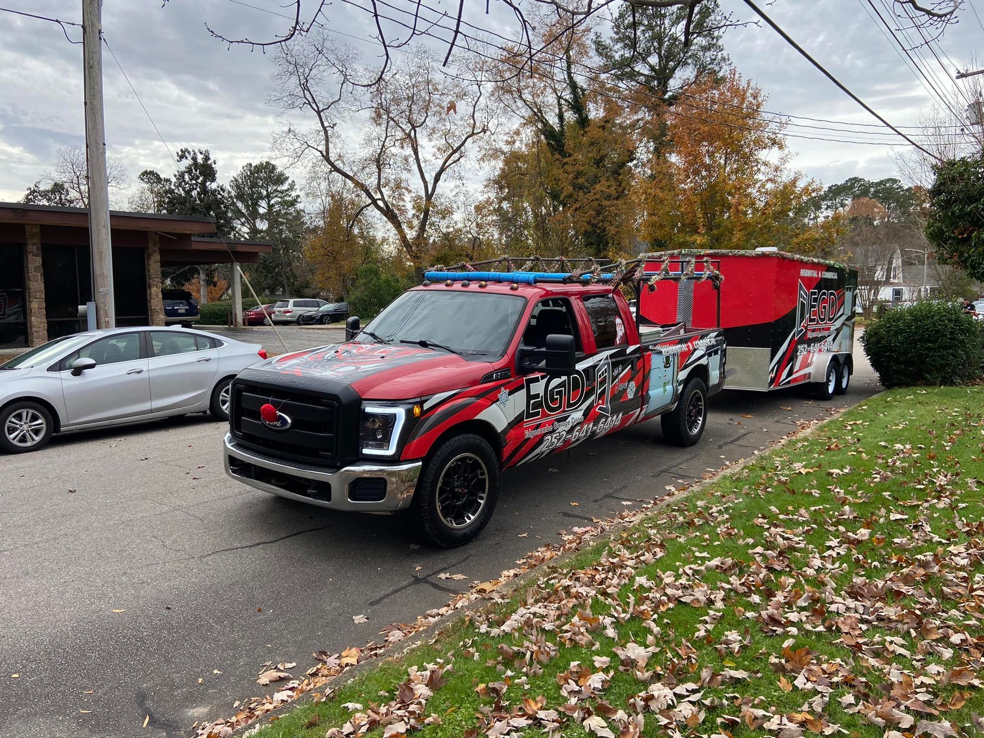 A red tow truck is driving down a street with a trailer attached to it.