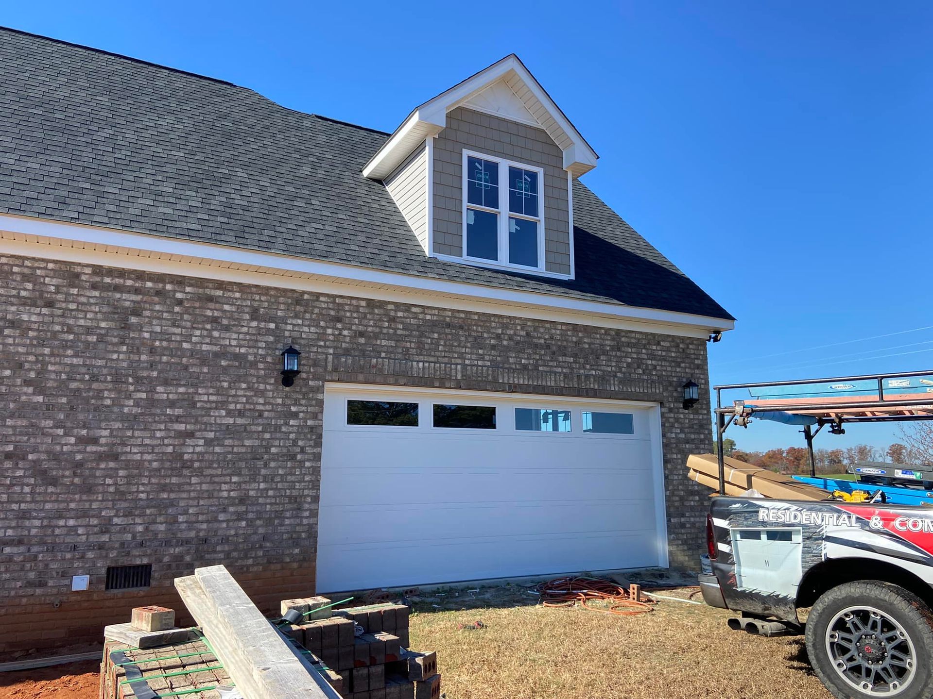 A brick house with a white garage door and a truck parked in front of it.