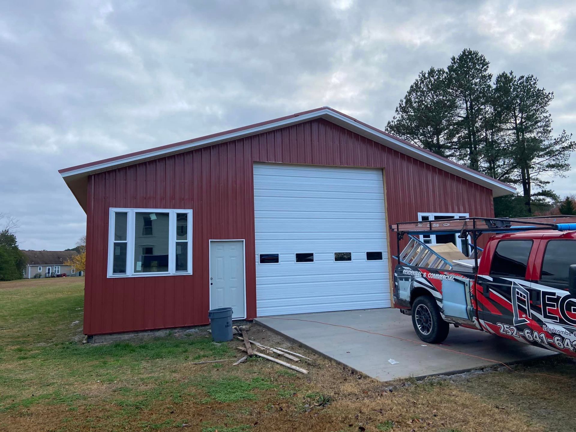A red garage with a white garage door and a truck parked in front of it.