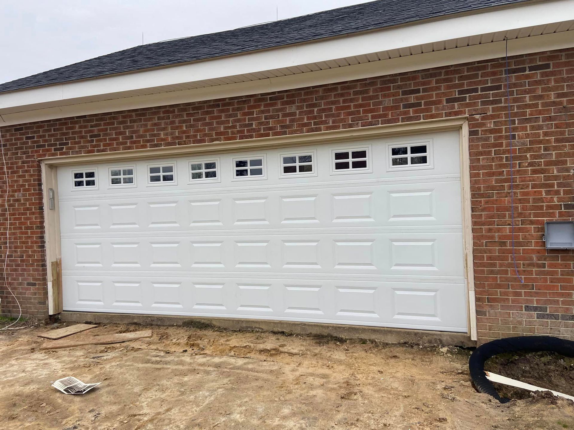 A white garage door is sitting on the side of a brick building.