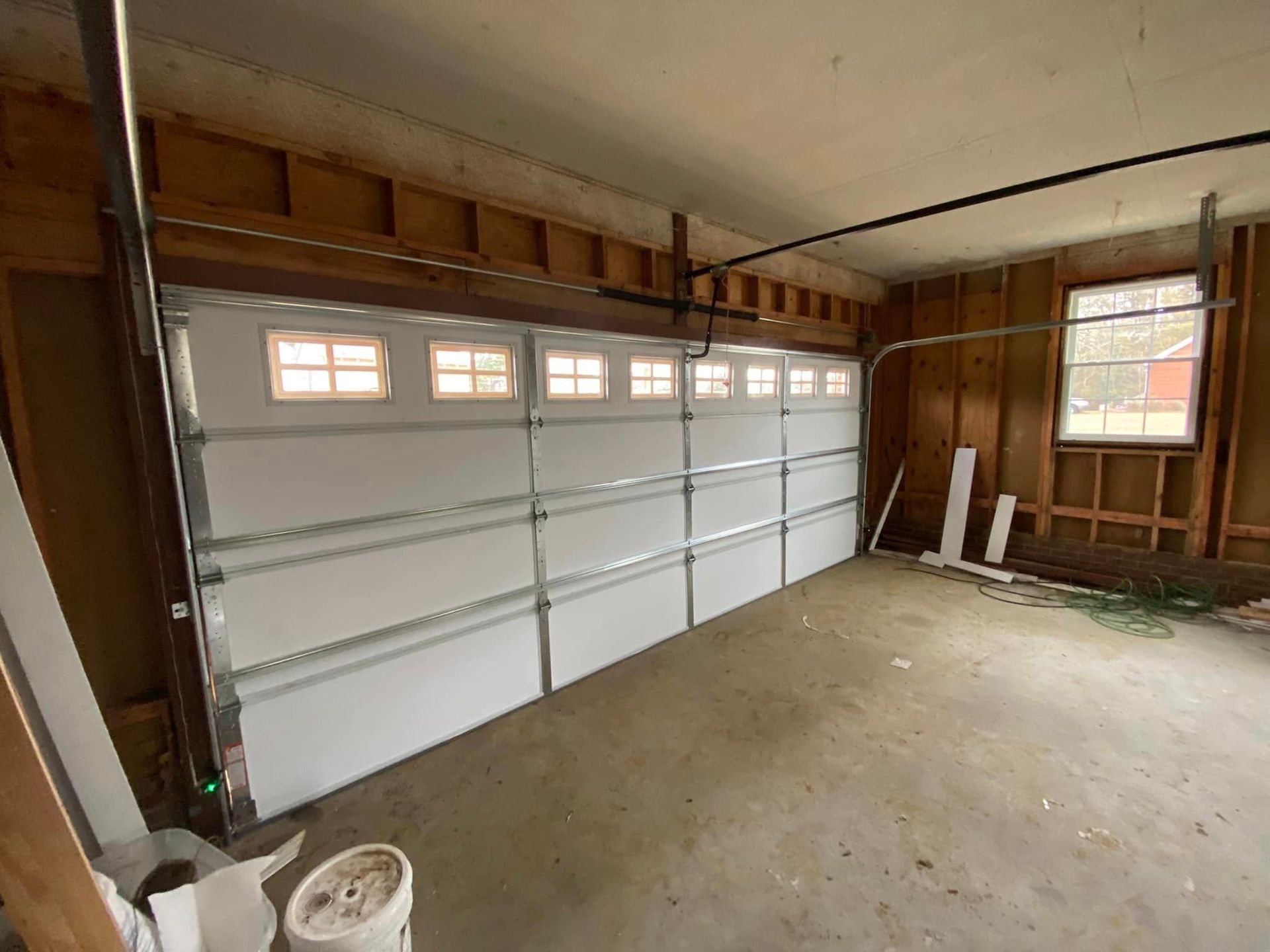 A garage with a large white garage door and a window.